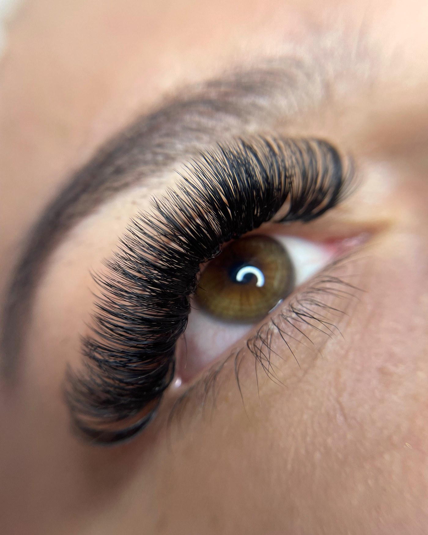 Close-up of a voluminous lash set on a warm ivory skin tone