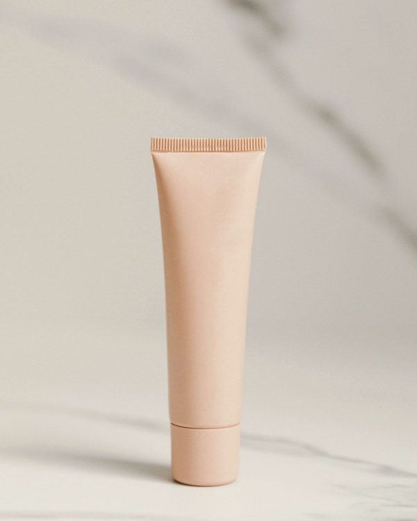Beige tube of lash bond remover on marble