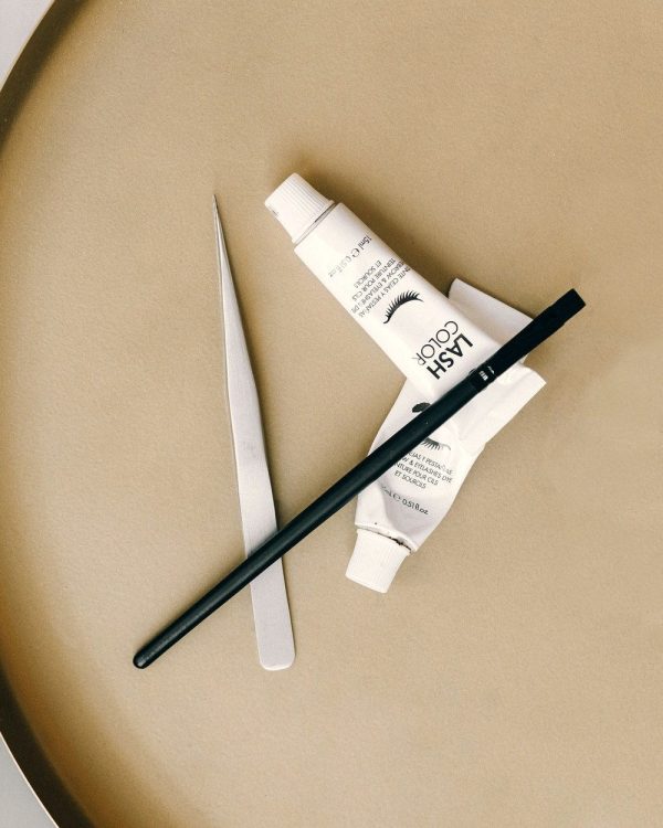 Flat lay of lash tools, tweezers and lash adhesive